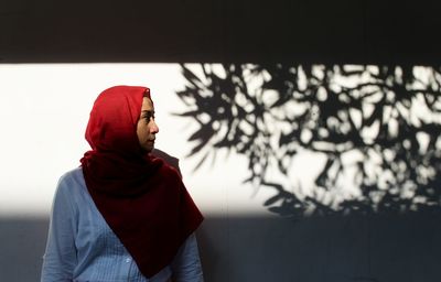 Woman wearing hijab while standing against wall