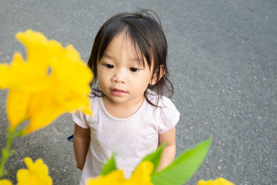High angle view of baby girl looking at flowers on plant
