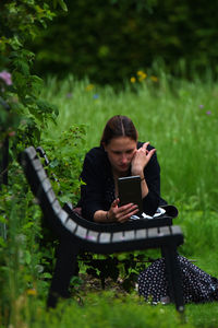 Woman using phone while sitting on grass