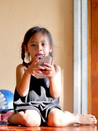 Portrait of happy girl using mobile phone at home