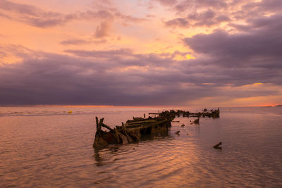 Sunken shipwreck from world war ii in the foreground close to the beach at sunrise