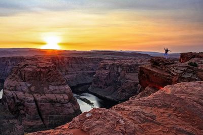 Mid distance view of person standing on cliff at horseshoe bend during sunset