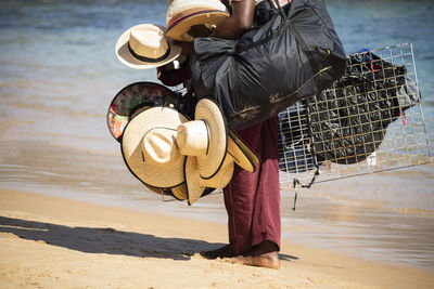 Street vendors walk on the sand of porto da barra beach in salvador, bahia.