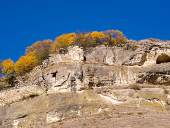 Low angle view of cliff against clear blue sky