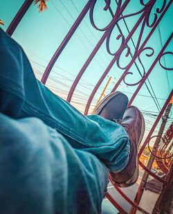 Low section of man relaxing against sky