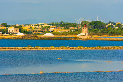 Scenic view of lake by buildings against sky