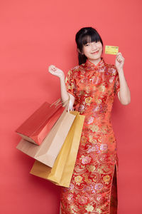 Woman holding umbrella against pink background