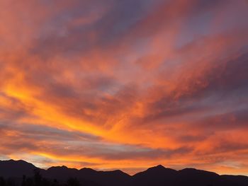 Silhouette mountains against dramatic sky during sunset