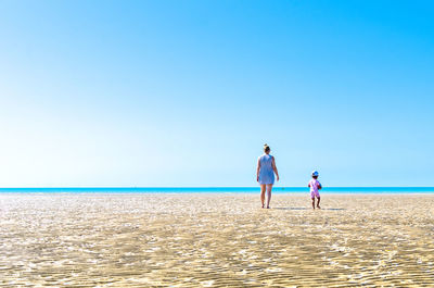 People on beach against clear sky