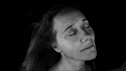 Close-up portrait of woman against black background