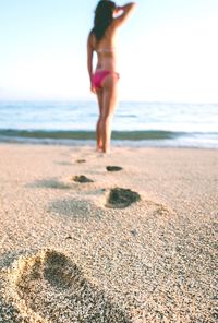 Rear view of woman wearing bikini standing at sea shore