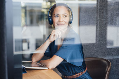 Thoughtful businesswoman wearing headset in soundproof cabin