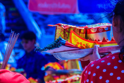 Rear view of person holding religious offerings in plate