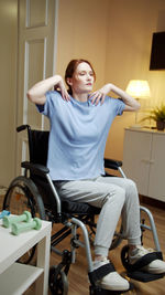 Young woman exercising while sitting on wheelchair