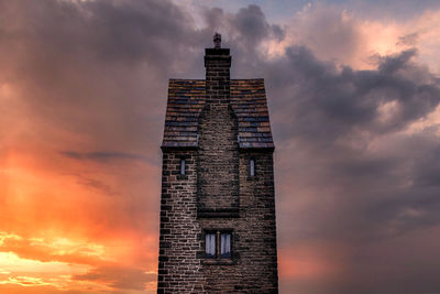 Low angle view of building against cloudy sky during sunset