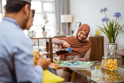 Smiling woman wearing hijab pouring drink in glass