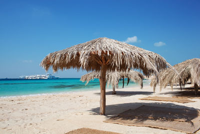 Thatched roofs at beach against sky