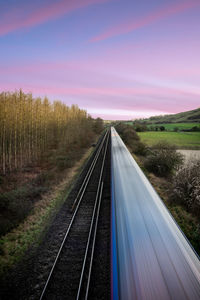 A moving train on a straight train track at sunset 