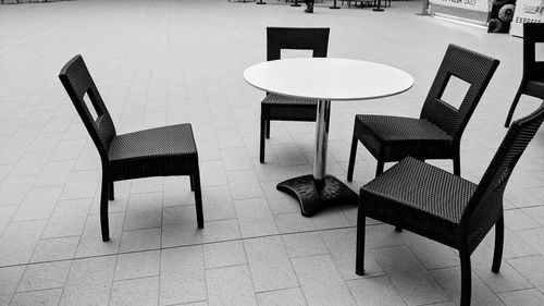 Empty chairs and tables on tiled floor