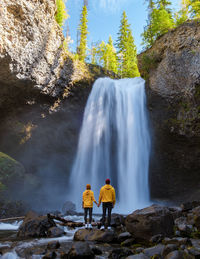 Rear view of man standing against waterfall