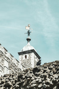 Low angle view of weather vane against buildings