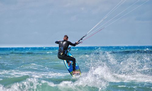 Man kiteboarding on sea against sky