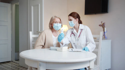 Doctor wearing mask checking patients temperature
