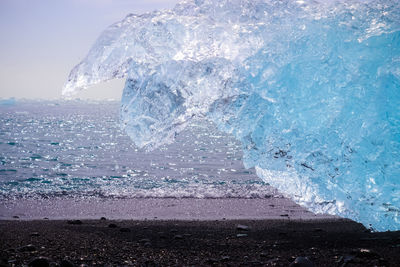 Diamond beach in iceland with blue icebergs melting on black sand and ice glistening with sunlight