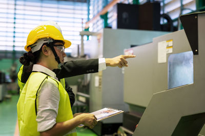 Side view of woman with man standing in factory