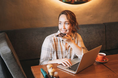 Young woman using mobile phone while sitting on table