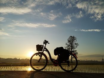 Silhouette man riding bicycle against sky during sunset