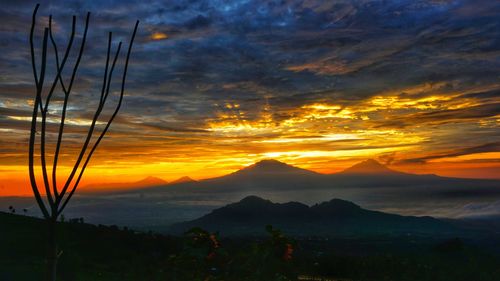 Scenic view of dramatic sky over silhouette mountains during sunset