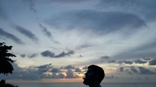 Silhouette woman by sea against sky during sunset