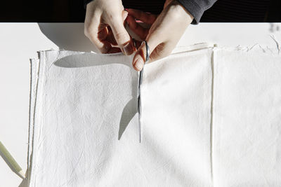 Crop sewer cutting piece of fabric on a table for making masks