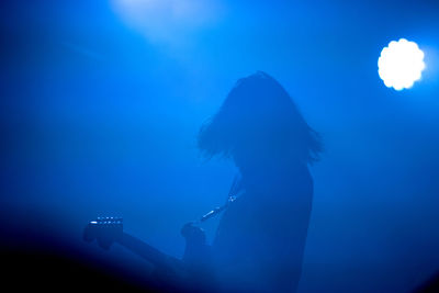 Side view of woman playing guitar at music concert