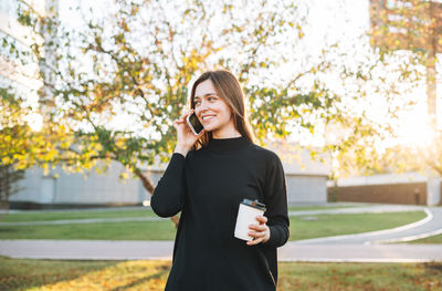 Portrait of young woman standing against trees