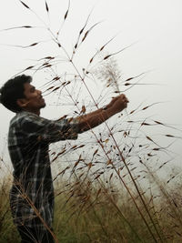 Side view of young man standing on land against sky