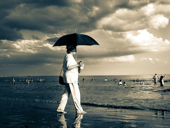 Men standing on beach against sky