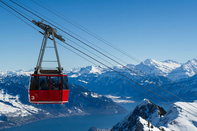 Overhead cable car over snowcapped mountains against clear sky