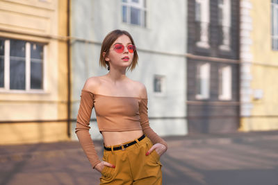 Beautiful young woman standing by buildings