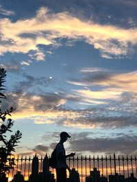 Silhouette woman standing by railing against sky during sunset