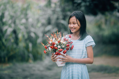 Beautiful young woman standing by pink flower