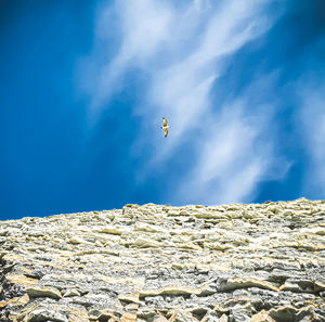 Low angle view of person paragliding against blue sky