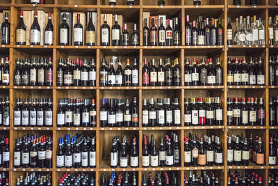 Full frame shot of wine bottles on shelves for sale at store