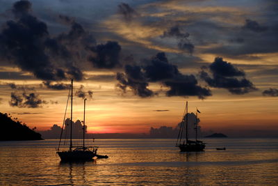 Silhouette sailboats in sea against sky during sunset