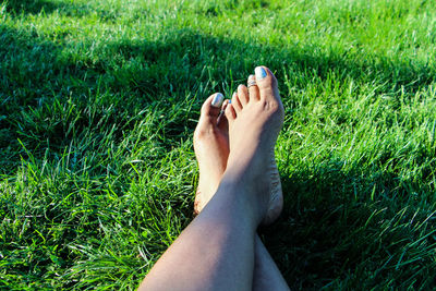 Low section of woman relaxing with legs crossed at ankle on grassy field