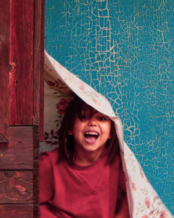 Portrait of smiling young woman standing against wall