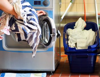 Cropped hands putting clothes in washing machine