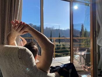 Rear view of men relaxing while looking at sky through window