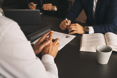 Midsection of lawyer with client in meeting at law office